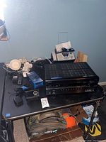 Full view of lot with Onkyo AV receiver, Brother fax machine, SiriusXM radio, and cords on black table.