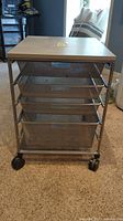 Front view of rolling mesh storage cart with four drawers on caster wheels, showing beige top and mesh drawers.