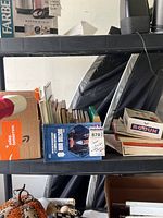 Shelf containing a blue box with stamps and some other boxed items.