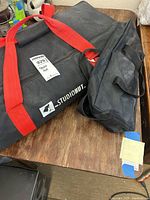 StudioHut black carry bag with red handles on wooden table, labeled 9291