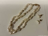 Full view of the multi-strand freshwater pearl necklace and the double strand pearl bracelet with small gold beads and earrings next to them.