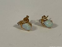 Front view showing pear-shaped opal drops and round aquamarine accents
