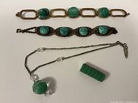Top-down view of entire lot showing two bracelets, a necklace, and a bakelite brooch piece.