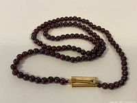 Full length view of the amethyst beaded necklace showing the gold tone clasp and bead arrangement.