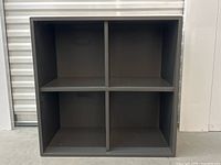 Front view of dark square 4-cubby shelf with even compartments showing condition and surface.