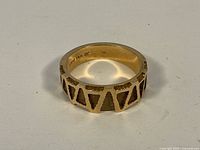 Front view of gold band ring showing triangular raised pattern and interior marking