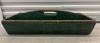 Side view of antique green painted wooden pine tool caddy showing handle cutout and worn paint