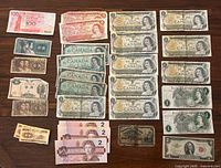 Flat lay of all banknotes arranged by type showing Canadian $2 bills on right and foreign notes on left
