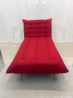 Front view of the red chaise lounge with an upright backrest, showing tufted upholstery and metal legs.