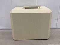 Front view of closed off-white hard plastic carrying case with handle