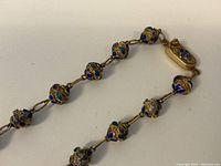 Photo showing the entire necklace chain with spherical filigree beads and enamel decoration, highlighting clasp and chain links.