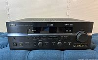 Front view of the Yamaha RX-V659 AV Receiver showing the volume knob, display panel, buttons and headphone jack.