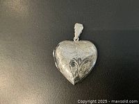Closed view of the heart-shaped sterling silver locket showing engraved floral designs on the front surface.