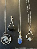Four sterling silver pendant necklaces displayed side by side on dark background showing distinct pendant styles and materials