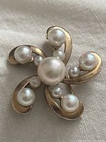Front view of the gold brooch showing pearls arranged in a swirl design.