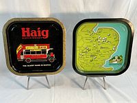 Photo showing the two vintage Scotch whisky serving trays side by side, Haig on the left with bus illustration, Green King on the right with map design.