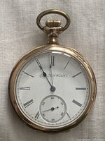 Front view showing white dial with Roman numeral hour markers and sub-second dial. Crown and bow at top visible.