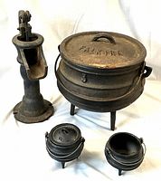 Photo showing four antique cast iron items: large cauldron with lid and handles marked 'FALKIRK', two miniature cauldrons (one with lid), and a hand water pump.