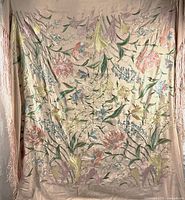 Full front view of shawl hung to display entire embroidered floral pattern and fringe
