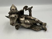 Front angle of reclining Ganesh statue showing detailed headgear, facial features, and arms holding symbolic items.