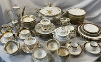 Full lot arranged on white tablecloth showing all 69 pieces including plates, cups, saucers, coffee pot, tureen and sugar bowl