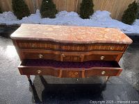 Front view showing three drawers, shaped front, one drawer open with purple velvet interior