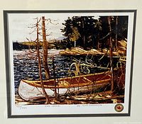 Close-up photo showing the image of the canoe by the water, signature of Tom Thompson, the handwritten edition number '986/999', title 'The Canoe', and a seal in the lower right corner.