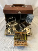 Various metal kitchenware items including a cube teapot, metal boxes, flask and an accessory kit with sewing items spread outside the case.