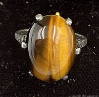 Close-up photo of the oval polished Tiger's Eye stone set in sterling silver prongs on the ring band.