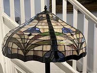 Close-up of stained glass shade showing cream panels with blue and green floral motifs
