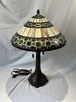 Full view of Tiffany style lamp showing stained glass shade and metal base with cord and plug