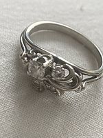 Angle view of ring showing central diamond and scrolling filigree design