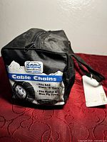 Black nylon storage bag with zippered opening showing a printed label that reads 'Laclede Chain Company, Cable Chains, Fits SAE Class S cars, Fits Radial or Bias Ply Tires.'