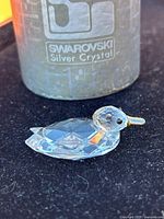 Photo showing Swarovski Silver Crystal container labeled 'Swarovski Silver Crystal' alongside the clear crystal duck figurine, highlighting the brand and authenticity.