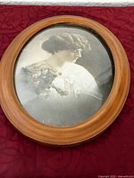 Front view of the vintage oval wooden frame housing a Victorian-style portrait of a woman, showing overall condition and design.