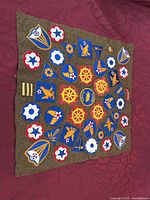 Full view of wool backing with numerous vintage embroidered military patches arranged in rows and columns.