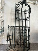 Front view of the closed wrought iron locking bottle cage section at the base of the wine rack with doors latched.