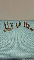 All 14 brass nativity figurines arranged in a row on a textured surface showing detailed crafting and condition.