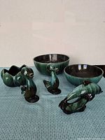 Full set of 3 bowls and 3 figurines in glossy green glaze laid out on a woven blue mat