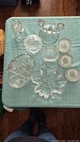 Top view of the crystal assortment showing all pieces including dishes, candlestick, snowman figurine, and round dishes on a blue cloth.