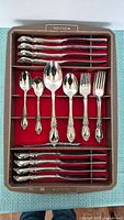 32-piece Oneida flatware set in a case, showing knives, spoons, and forks with ornate handles