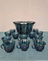 Punch bowl with 12 matching punch glasses arranged around it on a carpeted surface.