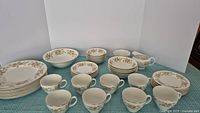 Set of Johnson Bros Snowhite patterned dinnerware pieces arranged on table including plates, bowls, teacups and serving pieces.