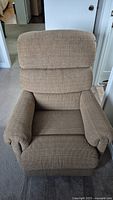 Front view of tan fabric reclining rocking chair showing padded backrest and armrests.