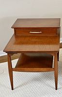 Front view showing stepped top and drawer with brass handle