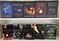Photo of 10 adult romance novels arranged on two shelves, 5 by Sylvia Day, 4 by Sylvain Reynard, and 1 by Deborah Harkness.