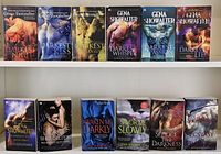 Photo showing twelve fantasy fiction romance novels by Gena Showalter arranged in two rows of six on a white shelf.