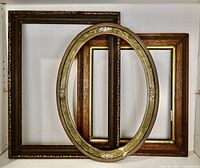 Three vintage wood picture frames including one large dark wood rectangular frame, one medium rectangular frame with gold trim, and one oval green painted wood frame with floral decoration.