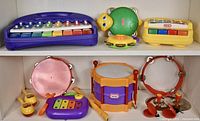 Full view showing a variety of colorful musical toys including pianos, tambourines, shakers, cymbals, drum, and a turtle toy.