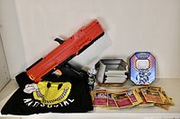 Kakashi figurine, Nerf blaster, Antisocial T-shirt, Pokemon card tin with cards displayed on shelf